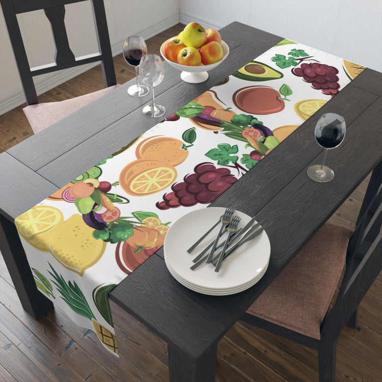 Colorful fruit designed table runner on a wooden dining table with wine glasses and plates.